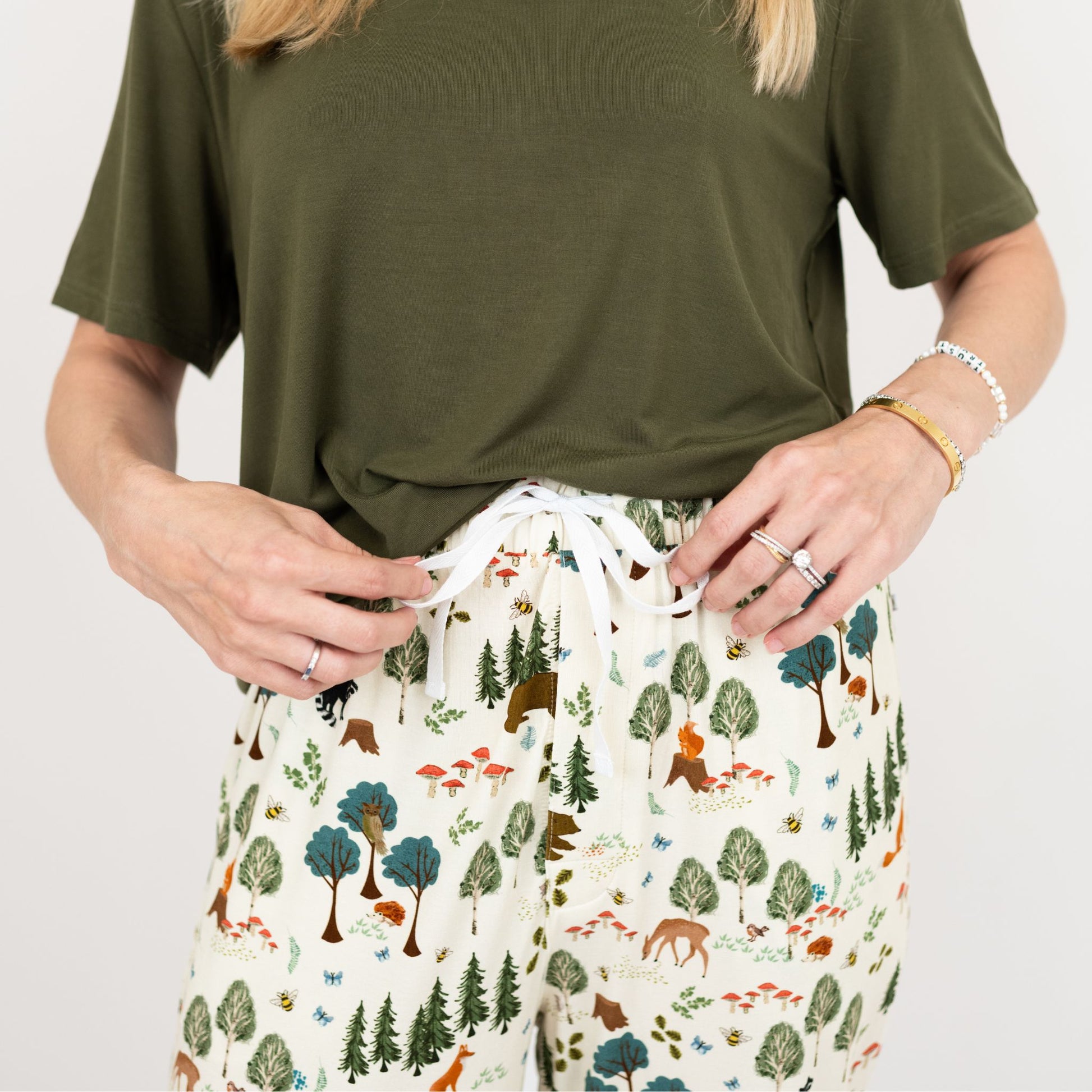 Person wearing a green t-shirt and patterned pants with animals and trees on a plain background