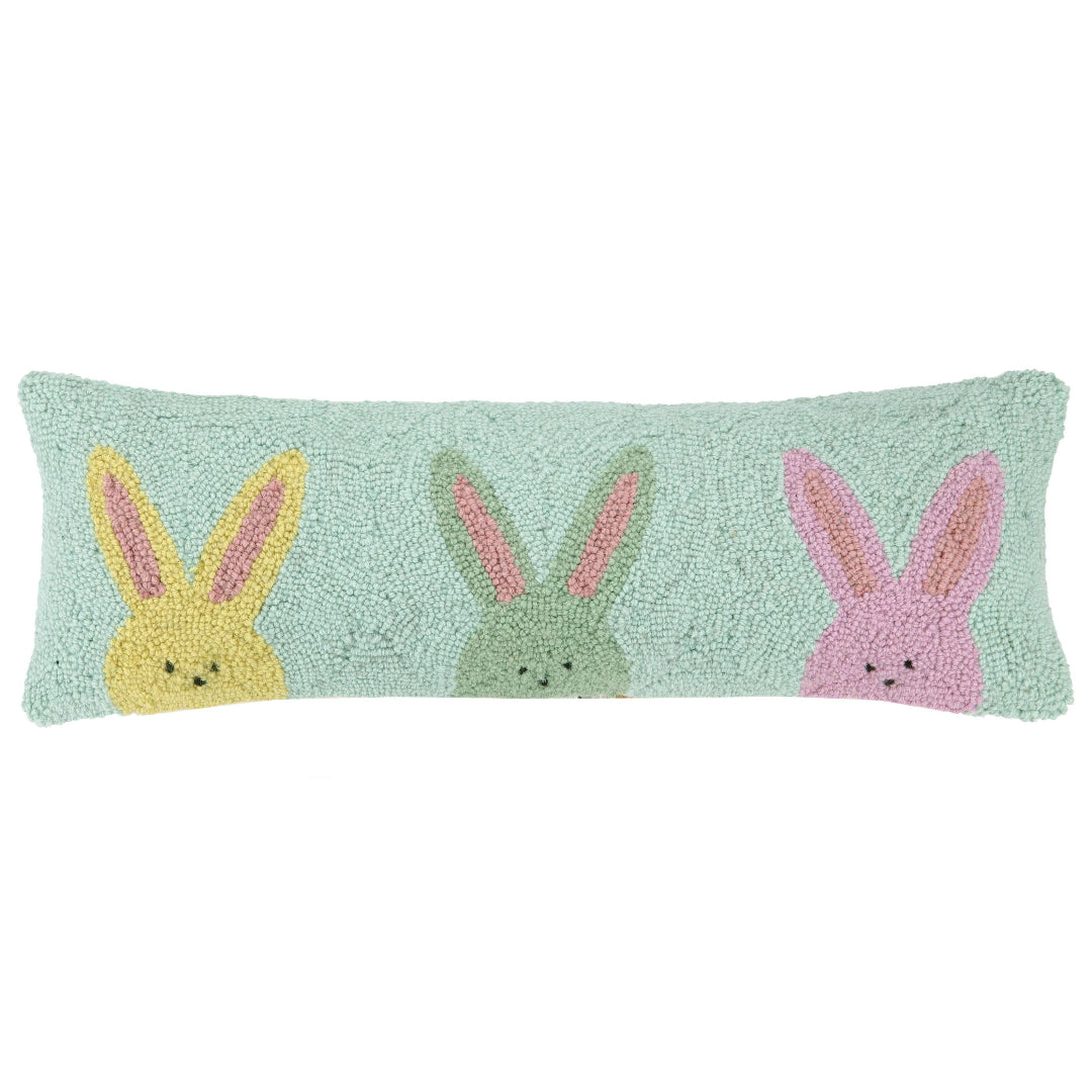 wool hook pillow that has a light blue background and 3 bunnies on the front in yellow, green, and pink