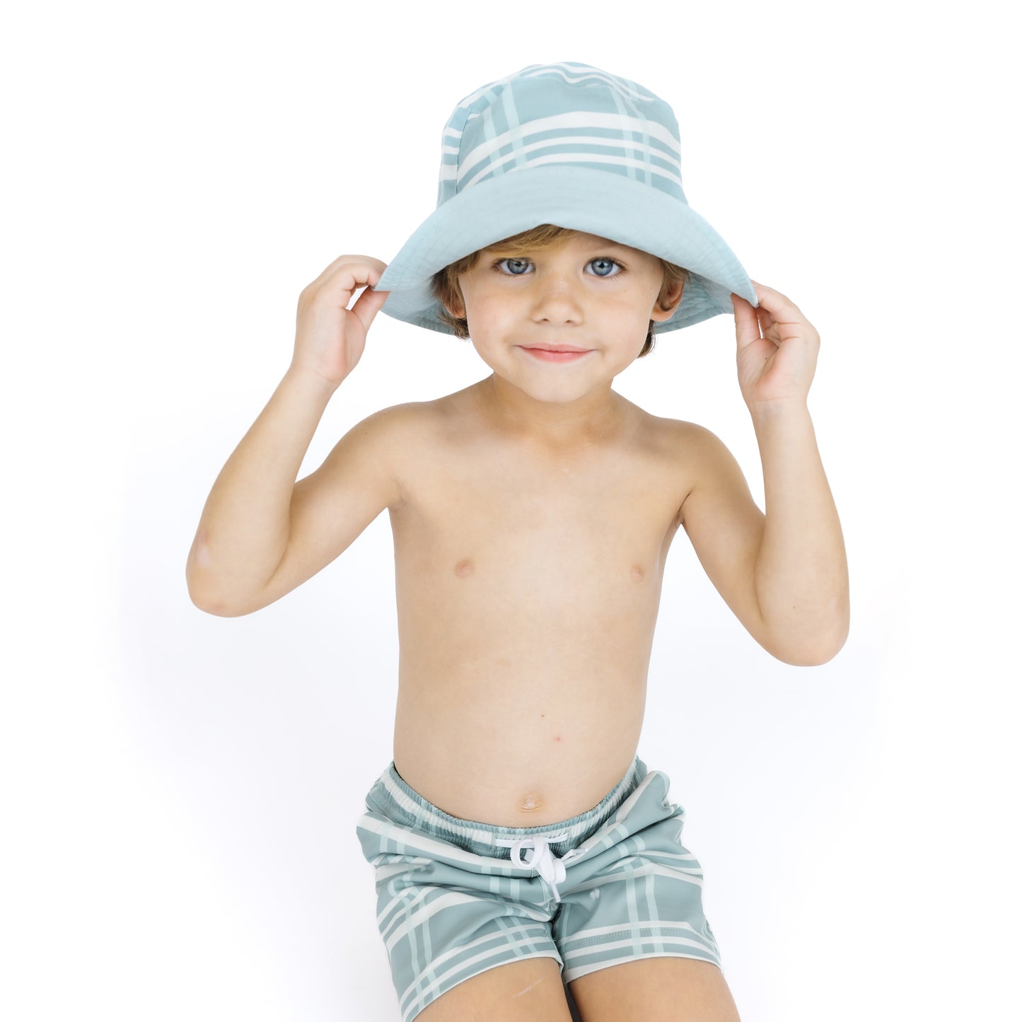 Child wearing a light blue sun hat and striped shorts on a white background