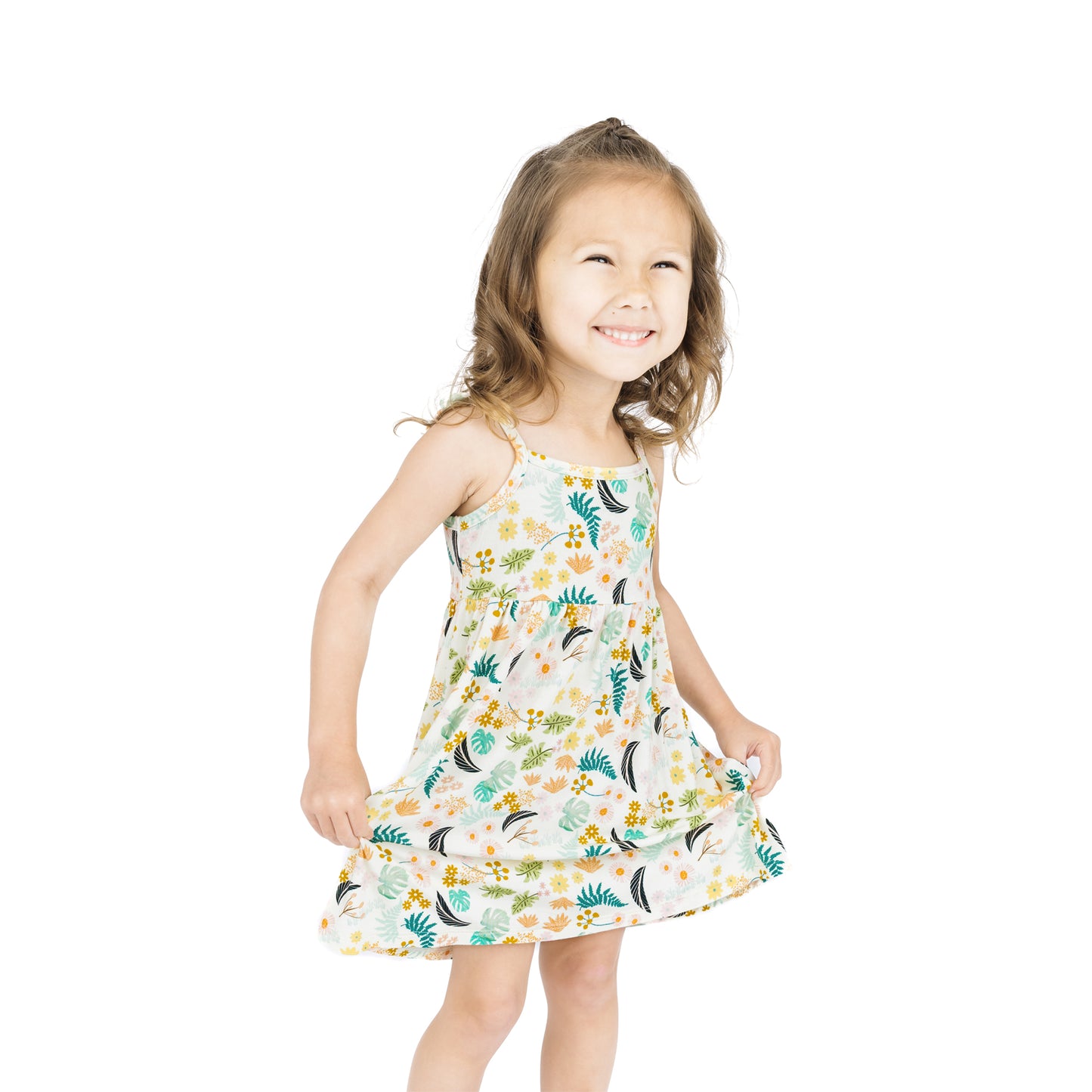 A young girl standing and smiling while wearing the Tropical Blooms botanical print bamboo sundress.