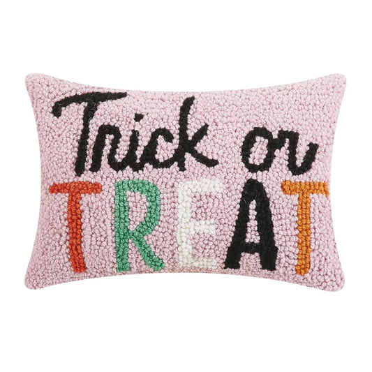 Pink decorative pillow that says trick or treat in multiple colors