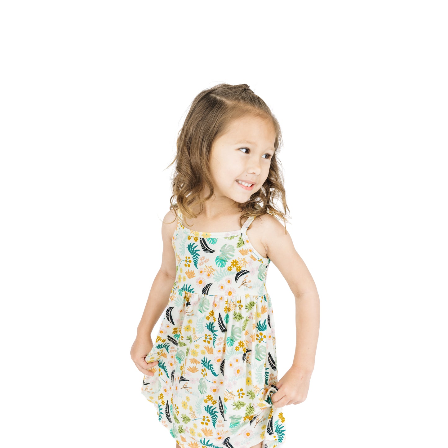 Close-up of a young girl wearing the Tropical Blooms sundress, showcasing the vibrant leaf and blossom pattern and dainty shoulder bows.