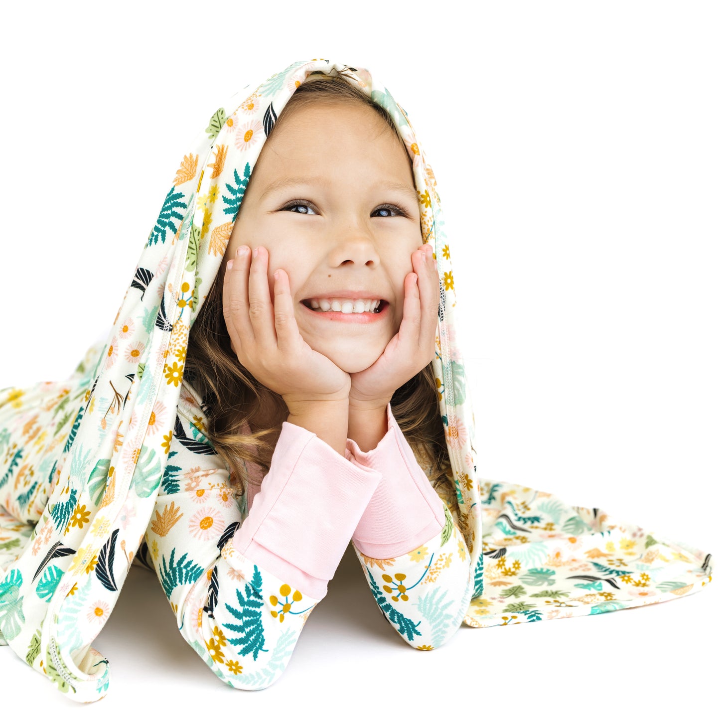 Toddler girl peeking out from under a Tropical Blooms floral bamboo blanket, perfect for snuggling and naps.