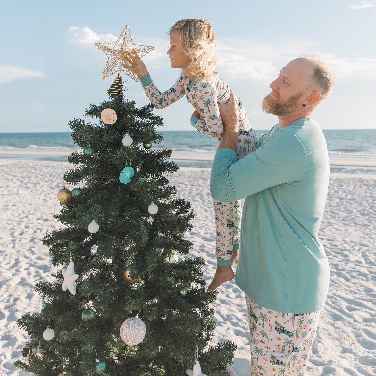Man and child decorating a Christmas tree on a beach