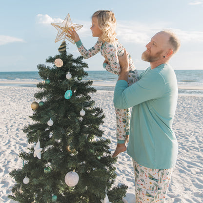 Man and child decorating a Christmas tree on a beach