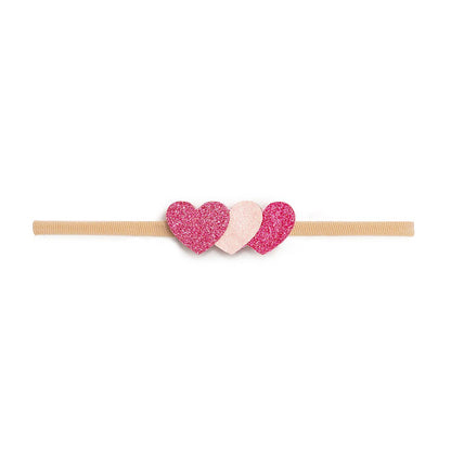 Headband with pink and white heart-shaped clips on a beige band against a white background