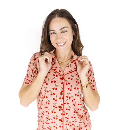 Woman wearing a pink pajama top with cherry pattern on a white background