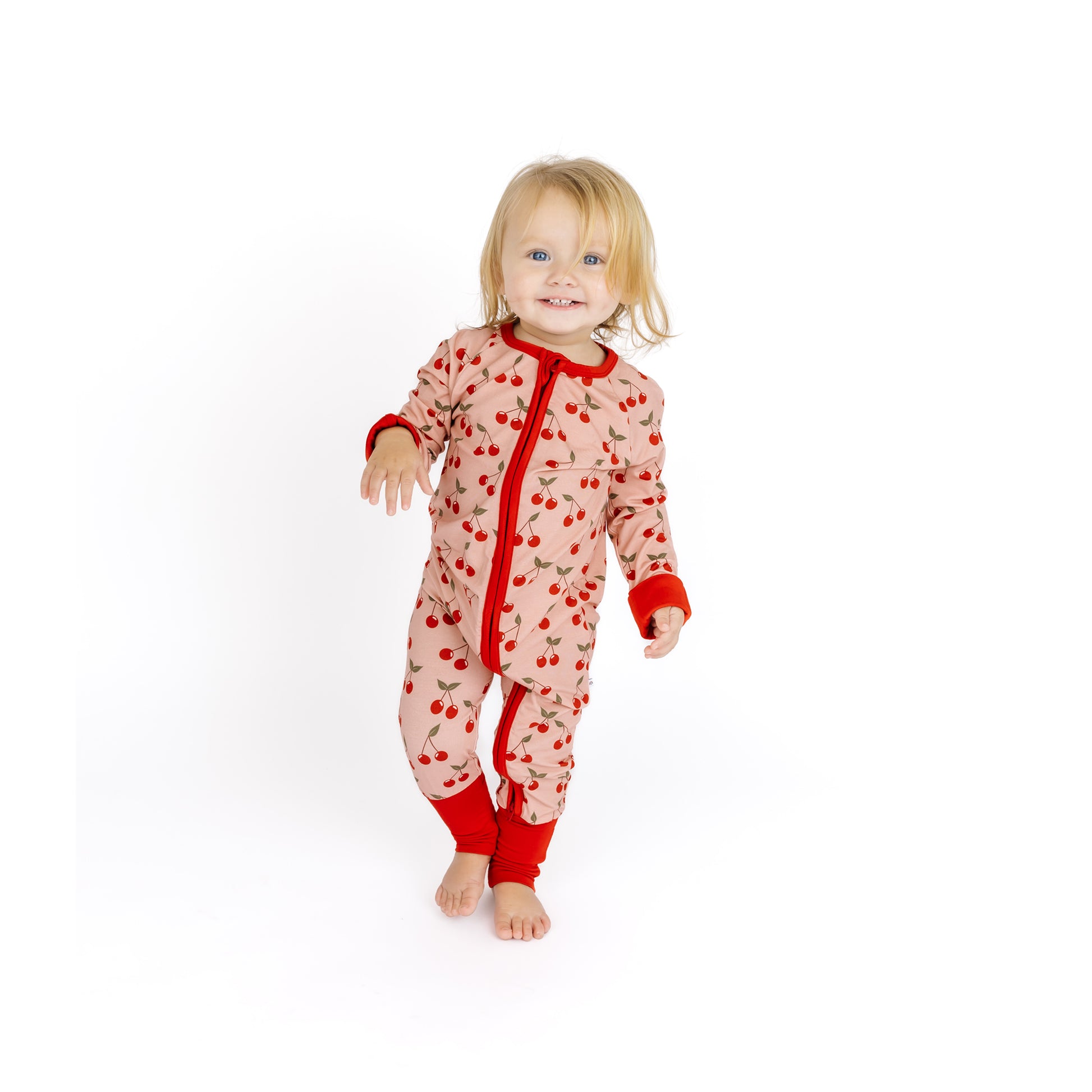 Child wearing a red and white patterned onesie on a white background