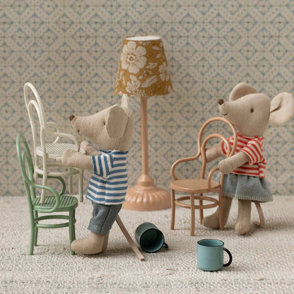 Two toy mice in a miniature room with furniture and decor.