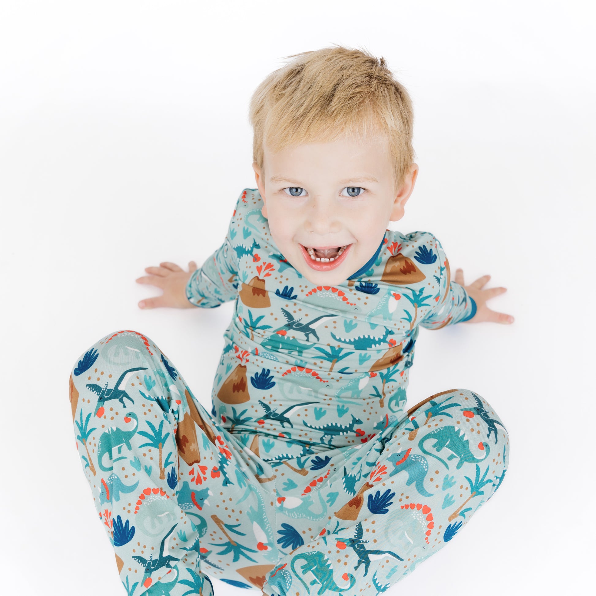 Kid playing in volcano dinosaurs bamboo long sleeve pajama set.