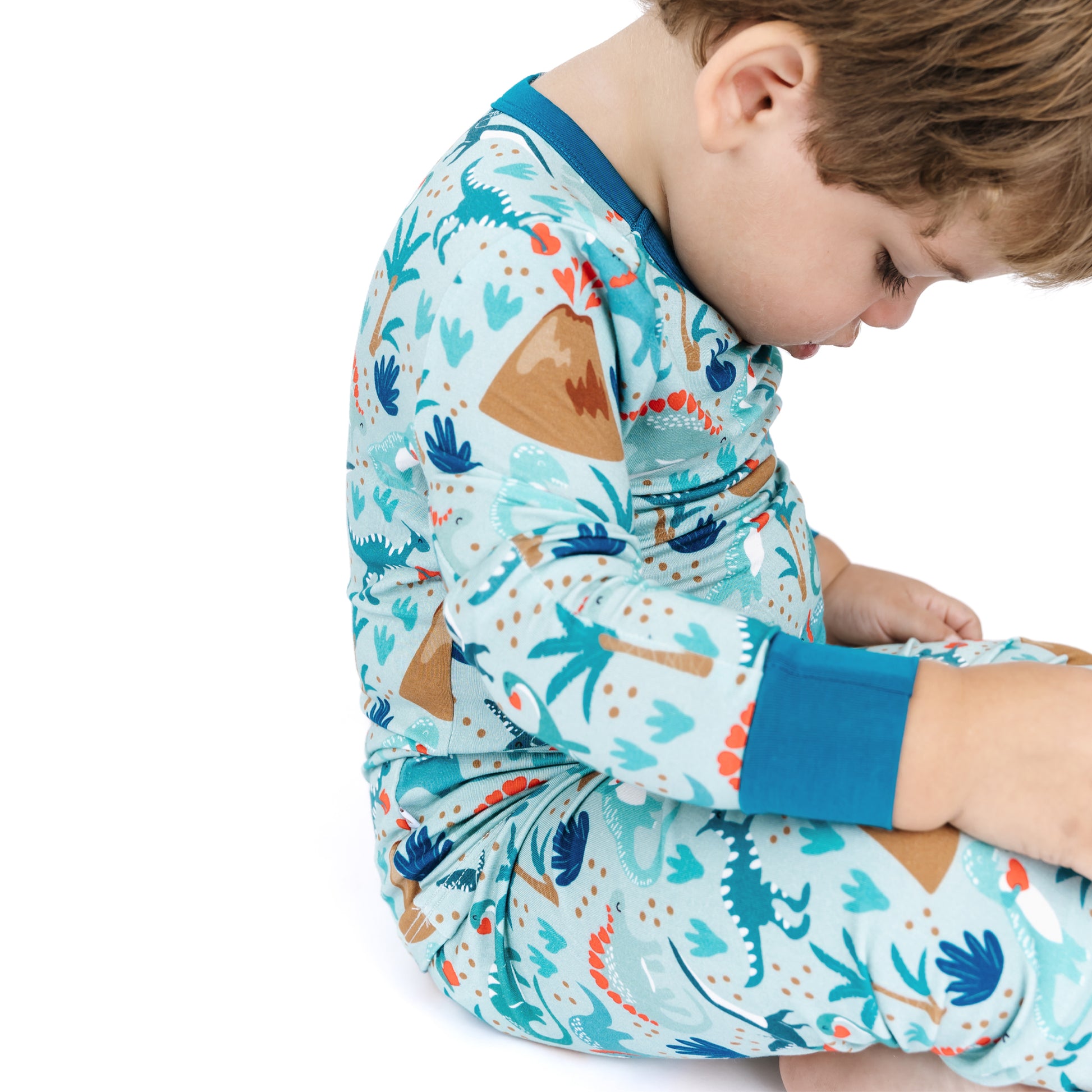 Side view of child wearing volcano dinosaurs bamboo pajama set.