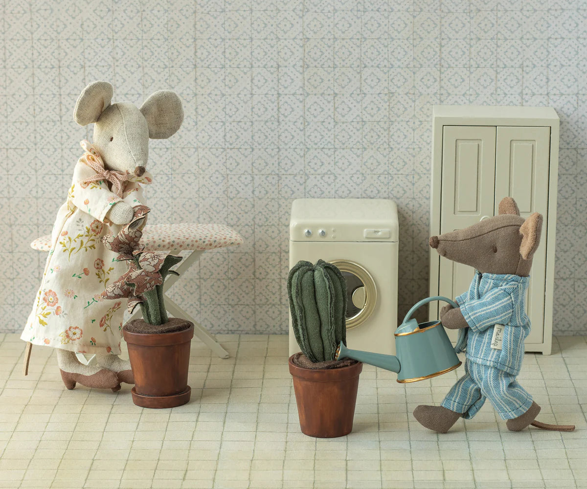 Two toy mice in a room with a washing machine and plants.
