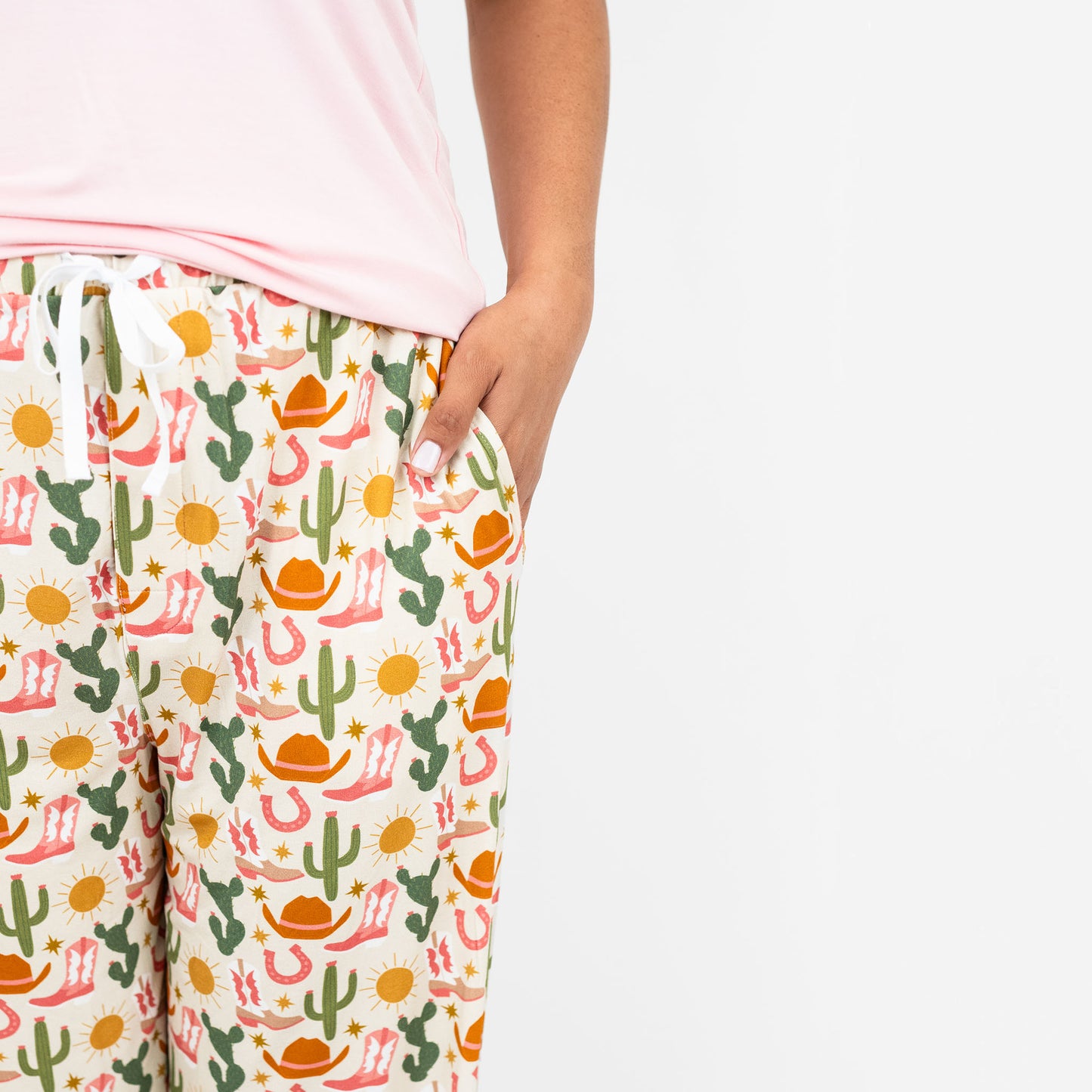 Close up of woman wearing our Emerson and Friends Hey Y'all relaxed pajama pants adorned with a charming cactus and flower print, ideal for cozy evenings at home.