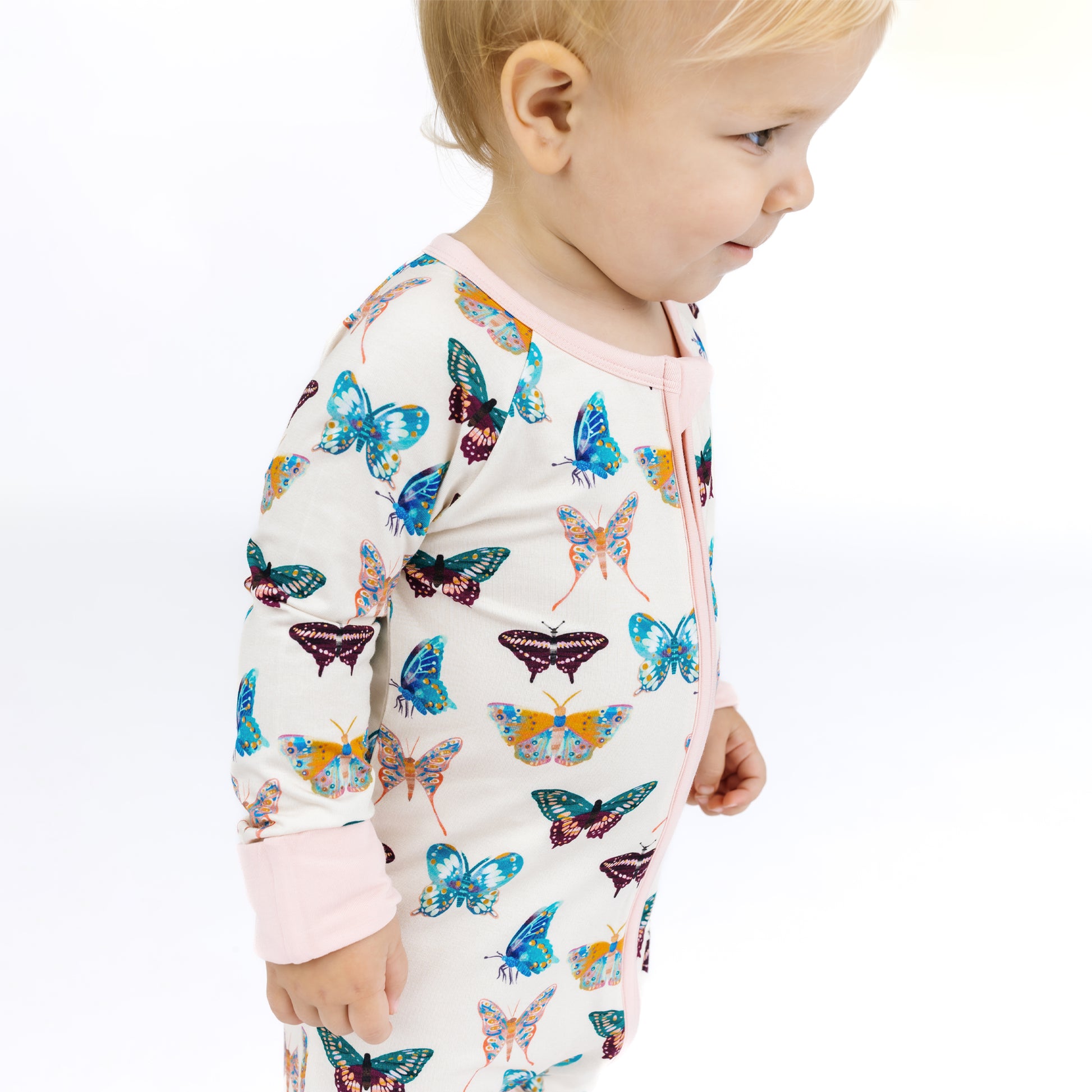 Child wearing a long-sleeve shirt with colorful butterfly pattern on a white background