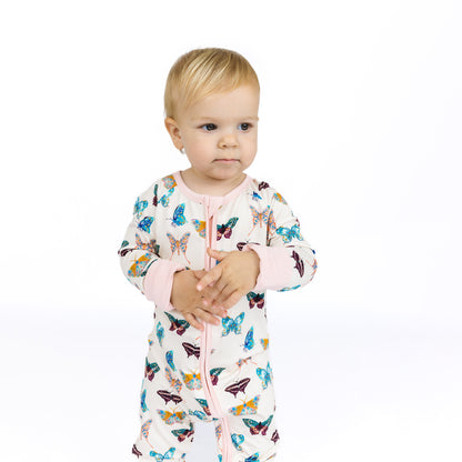 Baby wearing a colorful butterfly-patterned onesie on a white background