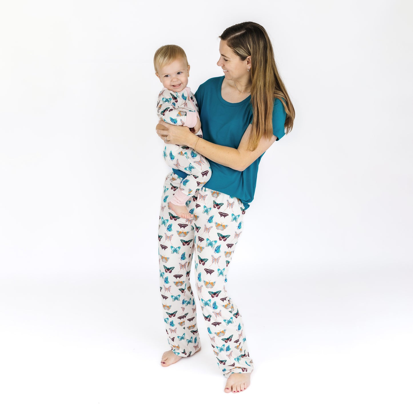 Woman and child wearing matching pajamas with a white background