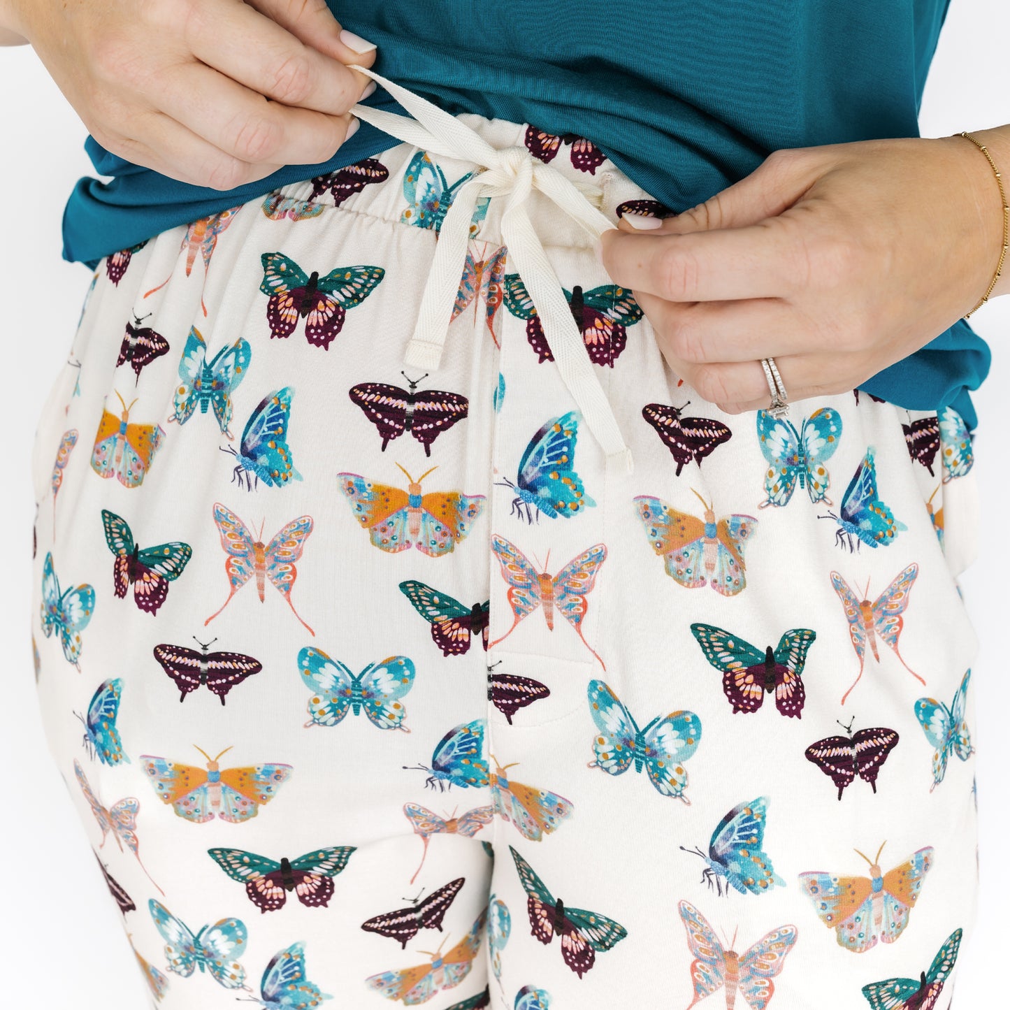 Drawstring bag with colorful butterfly pattern held by a person wearing a blue sweater.