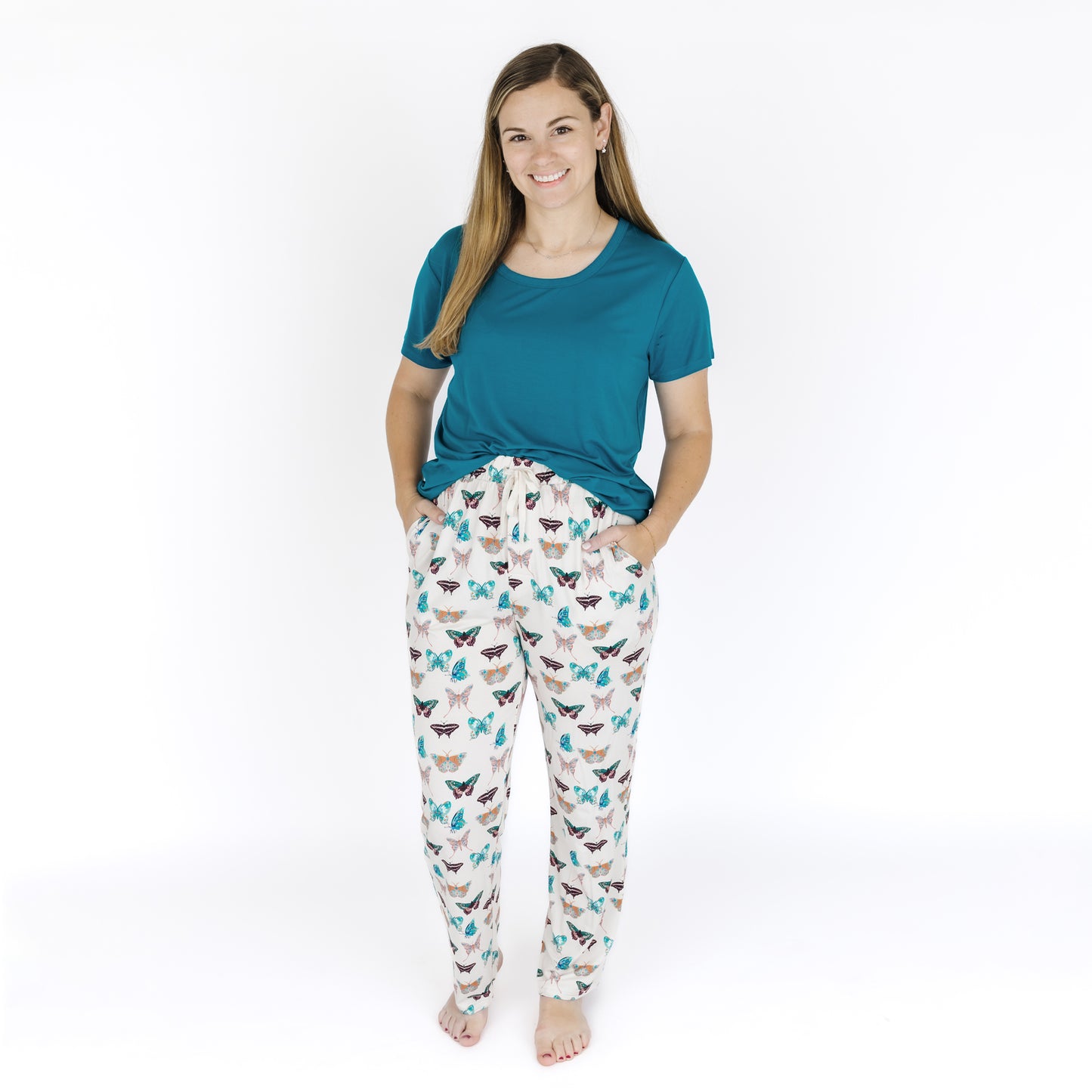 Woman wearing a teal shirt and patterned pajama pants on a white background