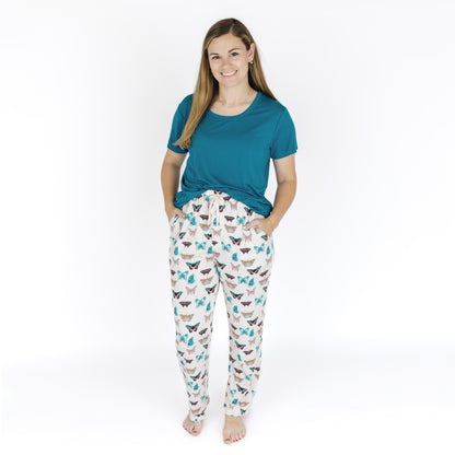 Woman wearing a teal shirt and patterned pajama pants on a white background