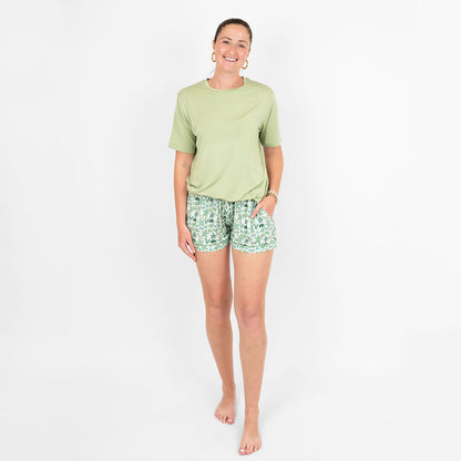 Smiling woman wearing our Save the Sea Turtles women's bamboo pajama shorts by Emerson and Friends. Featuring a soft sea-green background with hand-drawn turtles, seaweed, and starfish, these eco-friendly shorts are designed for ultimate comfort and sustainability.