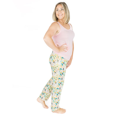 A woman standing in Tropical Blooms bamboo lounge pants paired with a pink tank top, showing the flattering unisex fit.