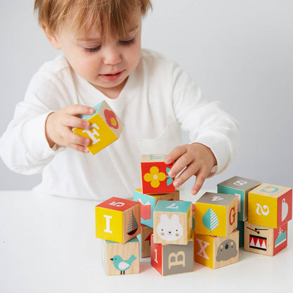 baby playing with multi colored wooden building blocks with different letters, numbers, and animals on them