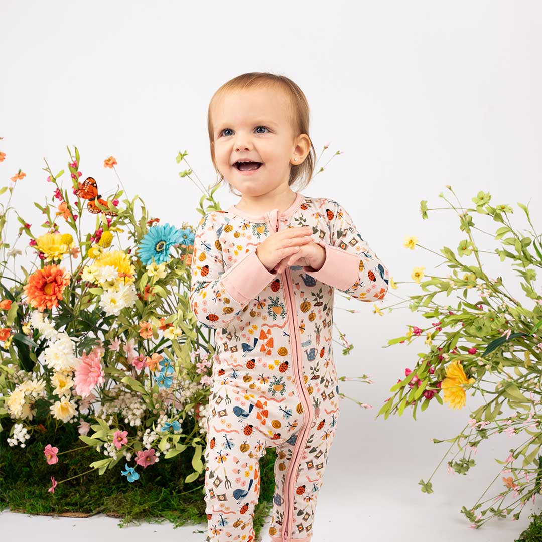Baby girl showcasing our convertible Garden Friends pajama. The print showcase ladybugs, butterflies, flowers, birds, snails, cactus, bees and plants. 