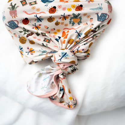 Baby showcasing our convertible Garden Friends pajama on a white background. The print showcase ladybugs, butterflies, flowers, birds, snails, cactus, bees and plants. 