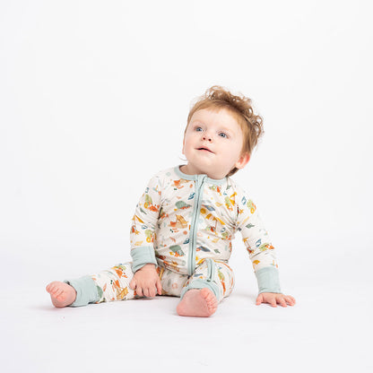 a baby boy sits on the floor in his "beach days" convertible. the "beach days" print is a scattered print of beach umbrellas, beach balls, sand buckets and shovels, coral, shells, beach chairs, seagulls, flipflops, and sunglass mixed in a orderly and creative way. 